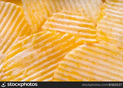 Yellow crispy ridged potato chips close up. Food background, banner, header, wallpaper.