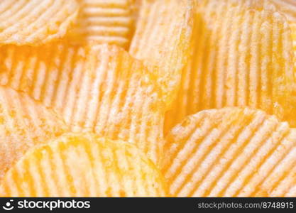 Yellow crispy ridged potato chips close up. Food background, banner, header, wallpaper.