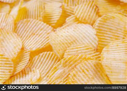 Yellow crispy ridged potato chips close up. Food background, banner, header, wallpaper.