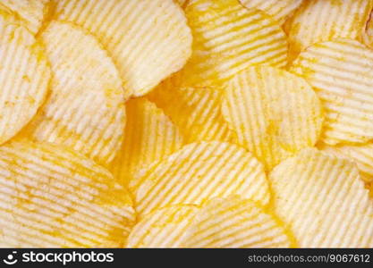 Yellow crispy ridged potato chips close up. Food background, banner, header, wallpaper.