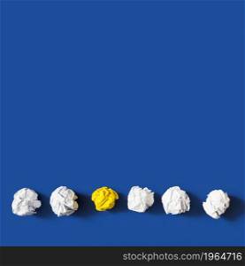 yellow crumpled paper ball among white balls against blue background. High resolution photo. yellow crumpled paper ball among white balls against blue background. High quality photo