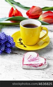 Yellow cup with tea,bouquet of tulips and symbolic heart