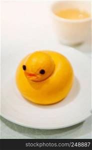 Yellow cute duck shaped Baozi chinese steamed bun on white plate