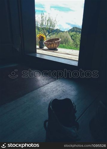 Yellow dandelion flowers in clay jug and wicker bowl, on wooden veranda background with mountains in distance. Still life in rustic style. Daylight, hard shadows. Countryside lifestyle concept