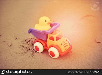 Yellow duck toy and colorful car on sand in the beach / Happy holidays for kids Children beach summer holidays