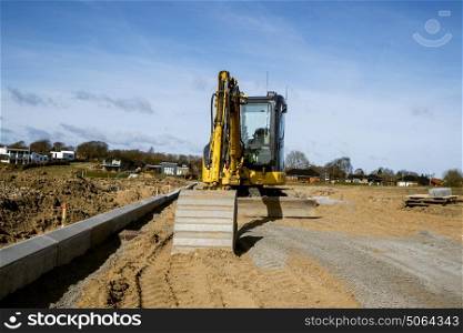 Yellow excavator digging on a construction site on a sunny day with blue sky