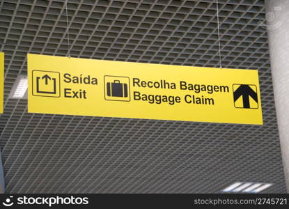 yellow exit and baggage claim sign at a international airport (hanging on a ceiling)