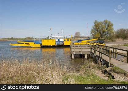 Yellow ferry in river landscape docked at landing stage on levee