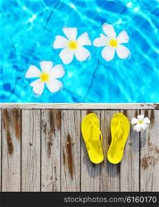 Yellow flip-flops by a swimming pool