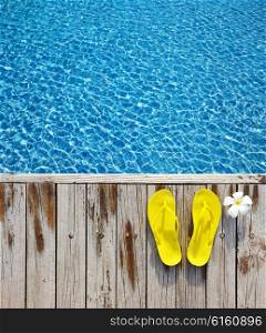 Yellow flip-flops by a swimming pool