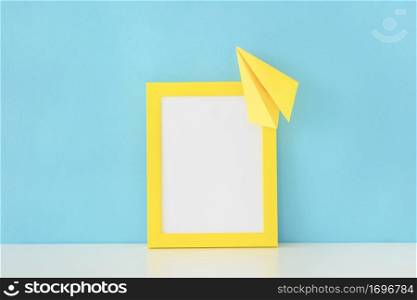yellow frame paper plane front blue wall