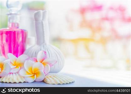Yellow Frangipani flowers with herbal compress stamps , pink lotion bottle and shells at summer nature background. Spa or wellness background