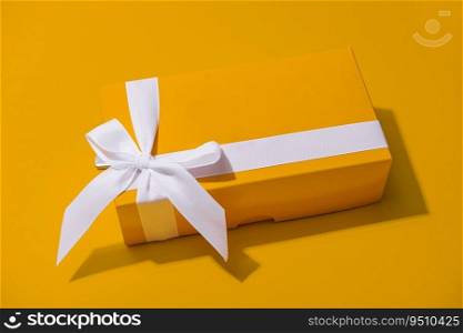 Yellow gift box with white ribbon isolated on yellow