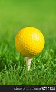 yellow golf ball on a tee over green grass outdoors