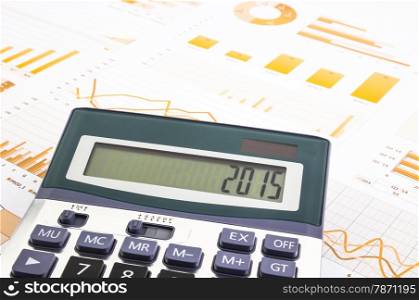 yellow graphs, charts, data and business report summarizing background with 2015 number on calculator, management project and planning goals for new year&rsquo;s resolution
