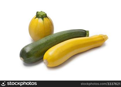 Yellow, green and round courgette on white background