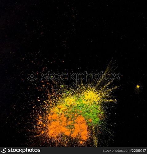 yellow green orange colored powder splatted black backdrop