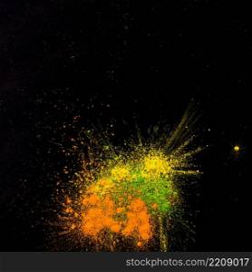 yellow green orange colored powder splatted black backdrop