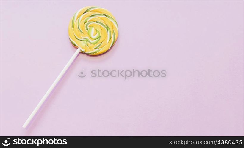 yellow green striped lollipop against pink background