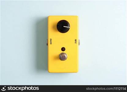 Yellow guitar effect pedal on blue background.