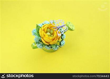 yellow handmade artificial flower, leaves with a glitter and a lot of paper roses in a miniature green watering can against a yellow background. and a purple butterfly view from the top. copy space.