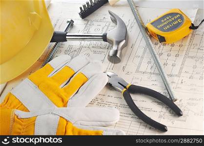 Yellow hardhat, gloves and hammer on drawings