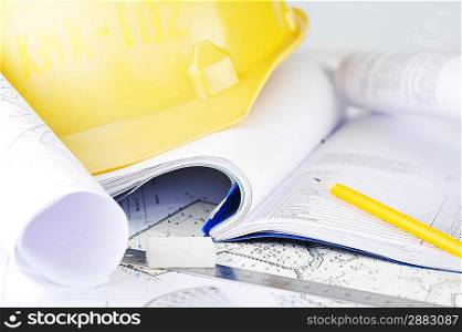Yellow helmet and heap of project drawings