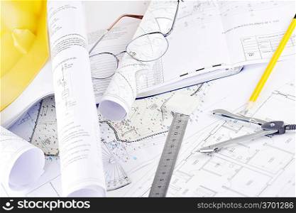 Yellow helmet and heap of project drawings
