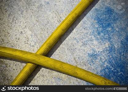Yellow hose pipes against blue and cement background