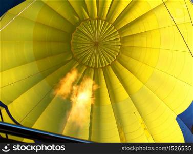 Yellow hot air balloon inflated with open propane flame. Hot air