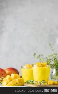 Yellow Indian mango yogurt drink Mango Lassi or smoothie with turmeric and saffron. Healthy probiotic Indian cold summer drink on blue background.