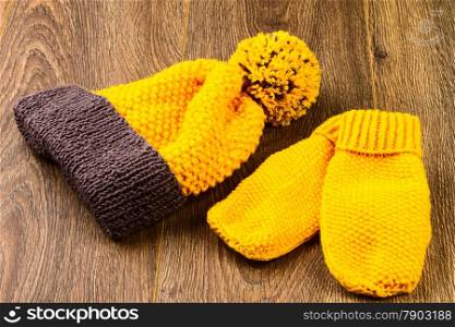 yellow knitting cap and mittens on wooden background