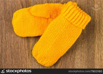 yellow knitting mittens on wooden background
