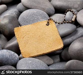 Yellow leather label with a chain on the pebbles