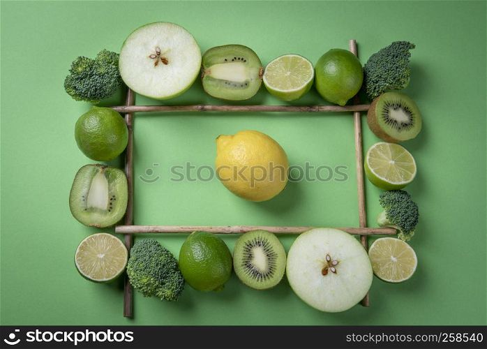 Yellow lemon fruit on green background in the middle of fresh fruits frame. Rich in vitamins food above view