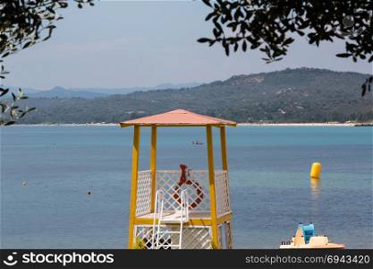 Yellow Lifeguard Tower on Beach in Front of the Sea with Orange Life Preserver, Hills in background. Yellow Lifeguard Tower on Beach