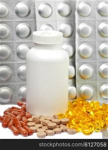 Yellow liquid capsules and silvery plates of medicines near a bottle