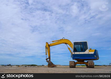 Yellow loader backhoe on pile dry wood chips with blue sky. Industrial in factory.