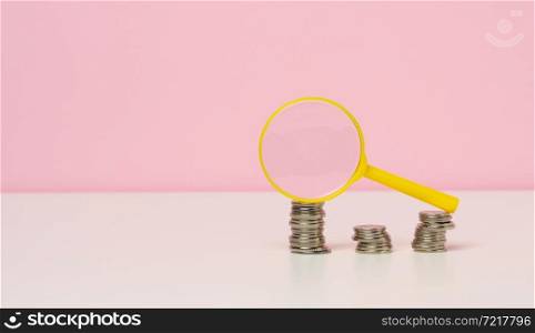 yellow magnifier and white coins on the table. Income growth concept, high percentage of investment. Search for new sources of income, subsidy
