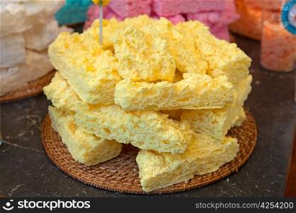 Yellow meringue cakes in pile on the wooden straw dish