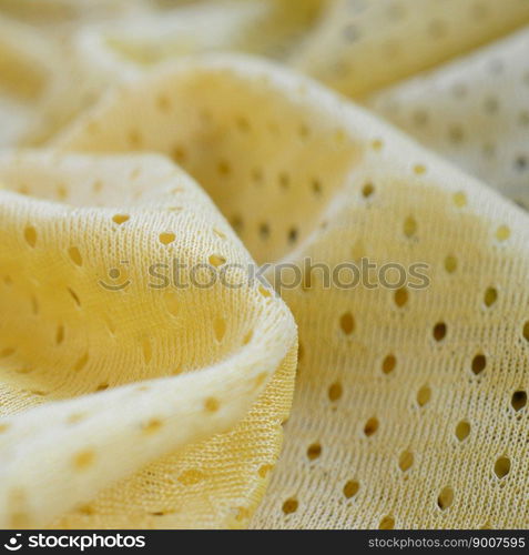 Yellow mesh sport wear fabric textile pattern background. Yellow color football jersey clothing fabric texture sports wear. Breathable porous poriferous material air ventilation with small holes. Yellow mesh sport wear fabric textile background pattern