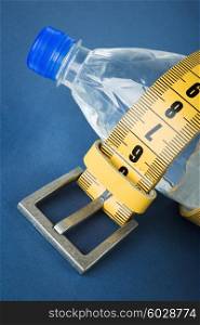 Yellow meter belt slimming and a bottle of water on a blue background