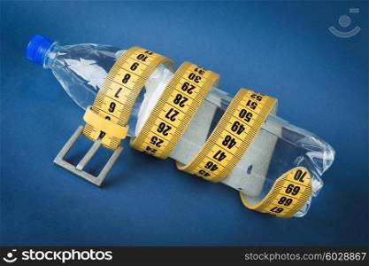 Yellow meter belt slimming and a bottle of water on a blue background