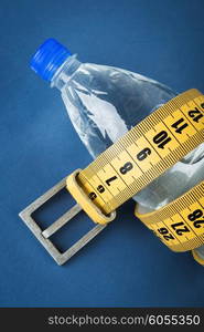 Yellow meter belt slimming and a bottle of water on a blue background