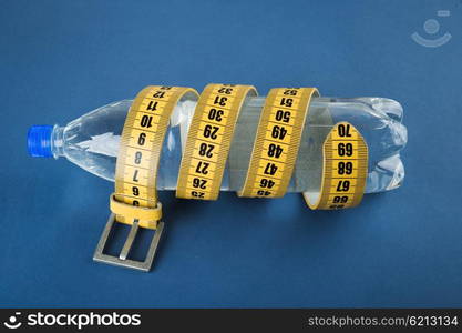 Yellow meter belt slimming and a bottle of water on a blue background