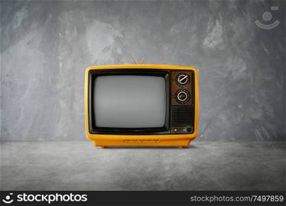 Yellow Orange color old vintage retro Television on cement table with background .