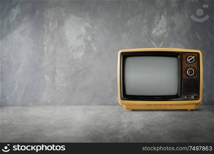 Yellow Orange color old vintage retro Television on cement table with background .