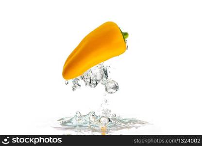 Yellow paprika falls under water with a splash. With lots of air bubbles upside down