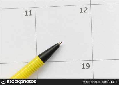 Yellow pen is placed on the calendar in the 12th day and have copy space for design in your work concept.