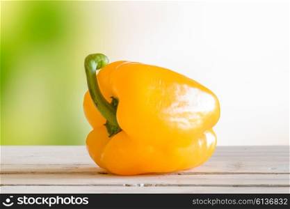 Yellow pepper on a wooden table in a garden